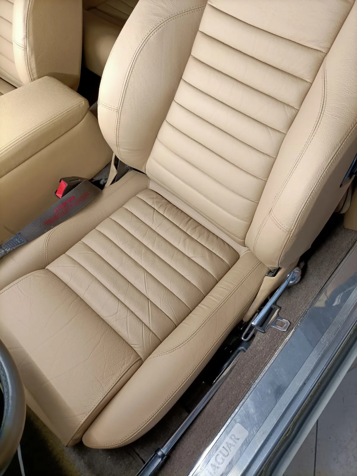 Popraskané sedadlo z béžové kůže v Jaguaru po renovaci