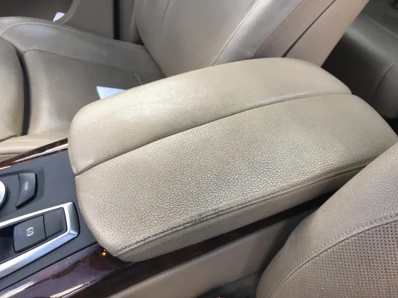 Før renovering: Armlæn i en BMW X5 efter rengøring og renovering af det lyse læder