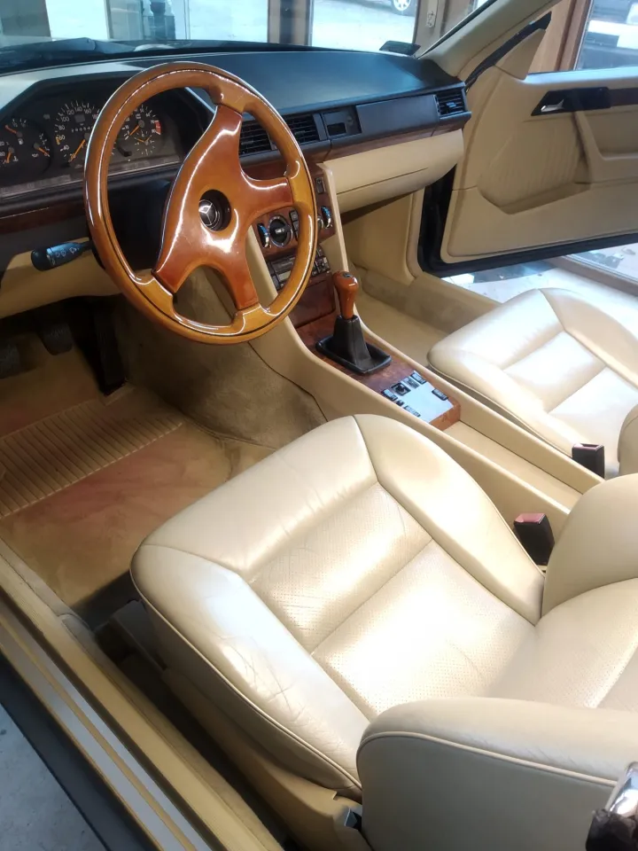 Krémová kožená sedadla a dřevěný volant v interiéru Mercedesu po renovaci